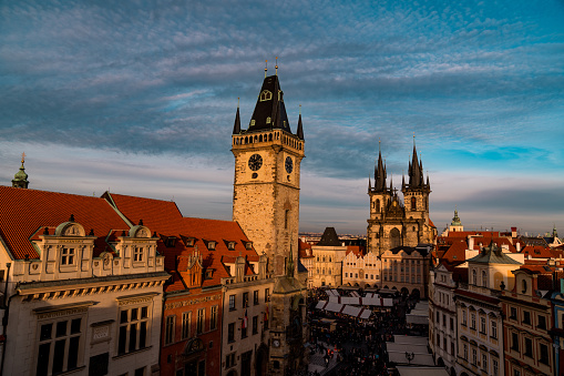 An elevated view of the Old Town Square and christmas market in Prague, the Town Hall with the astronomical clock is seen in the foreground, Tyn Church is seen in the background