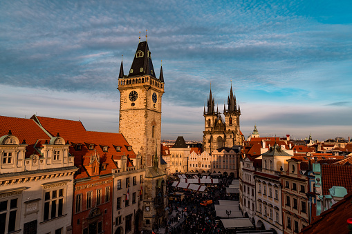 An elevated view of the Old Town Square and christmas market in Prague, the Town Hall with the astronomical clock is seen in the foreground, Tyn Church is seen in the background