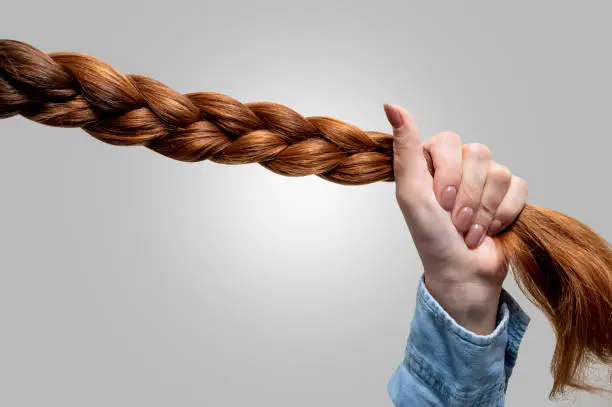 Photo of Woman's hand holding a braid of hair