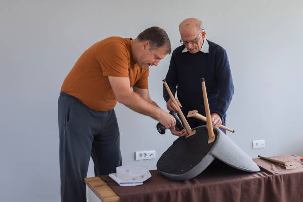 istock Senior man assisting his son  when assembling a chair 1435099424