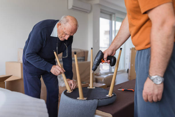 Senior man assembling a chair and having his son help him with a drill