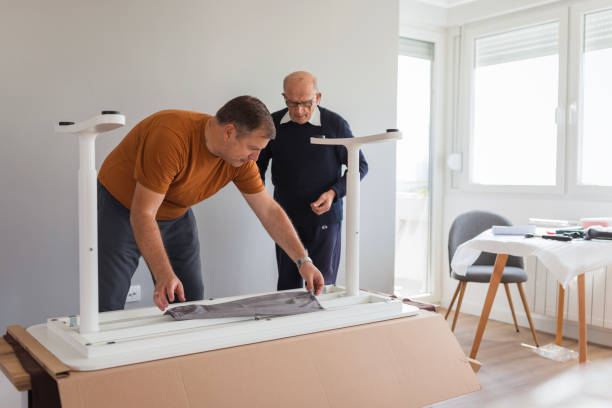 Elderly man helping his son using work tools to finish assembling new furniture
