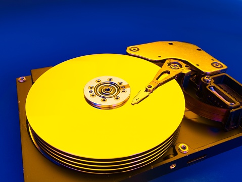 Shiny gold colored hard disk drive platters on a blue background. Conceptual image of the value of data storage in both business and personal life, Blue background with copy space.