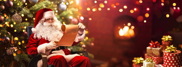 święty mikołaj siedzi w swoim pokoju i czyta świąteczną listę życzeń - santa zdjęcia i obrazy z banku zdjęć