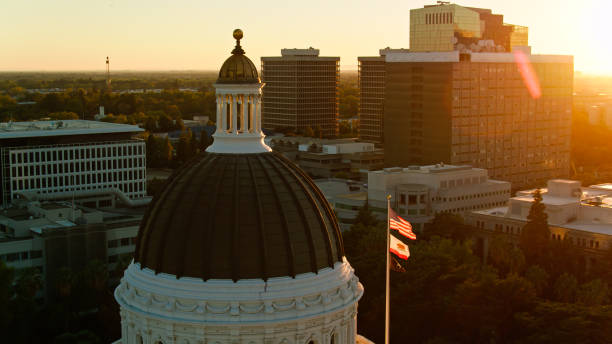 photo de drone de drapeaux américains et californiens flottant au-dessus du capitole de l’état au coucher du soleil - sacramento county flash photos et images de collection