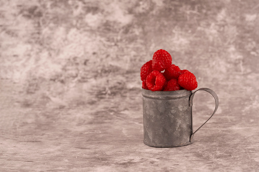 fresh raspberry in a cup on brown background Copy space