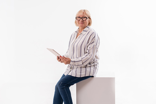 Studio shot of a senior woman using a digital tablet against a white background.