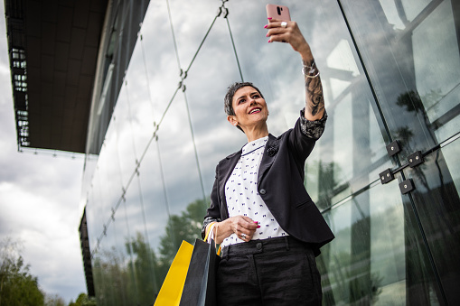 Shot of a mature woman using a mobile phone outside while shopping in the city