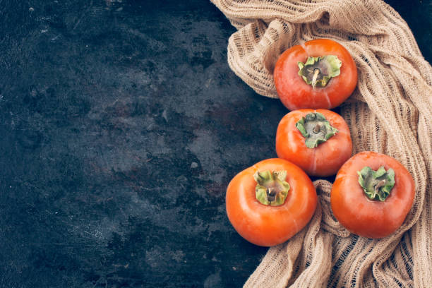 istock sweet ripe persimmon on a black table, cloth napkin 1435112974