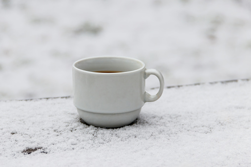 Cup of coffee on a snow covered table at winter
