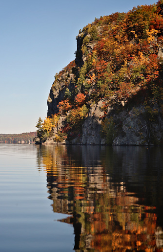 Mazinaw Rock, covered in colourful Autumn trees, reflected in Mazinaw Lake