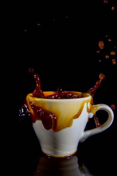 istock Splashes of coffee in a white cup on a black background. 1435118904