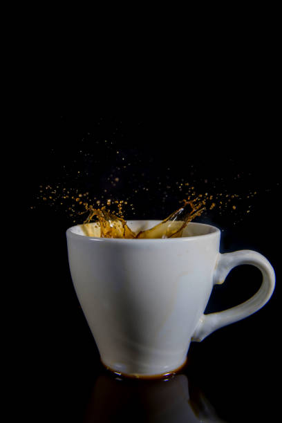 istock Splashes of coffee in a white cup on a black background. 1435118910