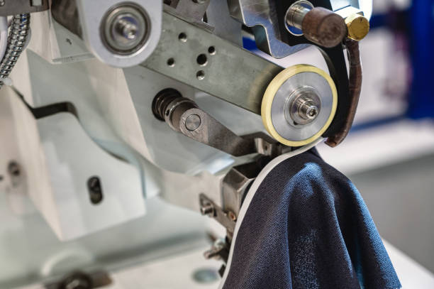 istock Machine sews cuff to dark blue fabric edge in workshop 1435119488