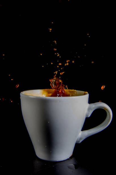 istock Splashes of coffee in a white cup on a black background. 1435119577