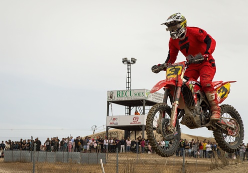 Motocross enduro rider in action accelerating the motorbike after the corner on dirt race track. Extreme off-road race. Hard enduro motorbike. Sky on background