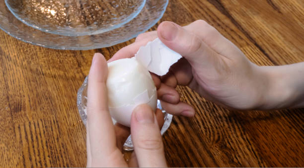 istock Woman peeling boiled egg on wooden background 1435123528