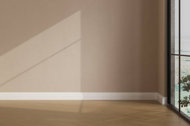 istock Realistic 3D render of room, beautiful sunlight and window frame shadow on beige blank wall, white skirting board in an empty room. New wooden parquet floor. Background, Interior. Front view. 1435125675