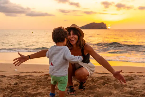 Photo of Mother hugging her son at sunset in Cala Comte beach on the island of Ibiza. Balearic