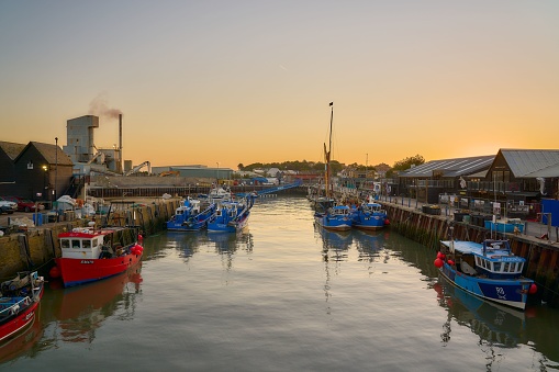 Whitstable, United Kingdom – October 06, 2022: Fishing boats docked in Whitstable harbor at golden hour