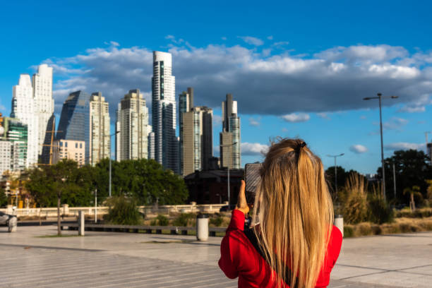mujer adulta rubia madura tomando una foto de teléfono inteligente de un grupo de edificios en el área de puerto madero, buenos aires. - turismo argentina fotografías e imágenes de stock