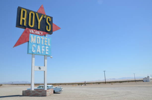 Barstow, California, USA - August 15, 2018: Barstow Sign with 1961 Corvette Convertible along Route 66. Barstow is located in Mojave Desert, san Bernardino County. American flag on background
