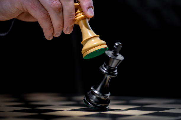 istock Male hand moving white piece on black king position 1435151194