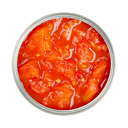Canned diced tomatoes, with tomato puree, in an opened can. Chopped tomatoes and tomato sauce. Tomato chunks, sealed into a can after having been processed by heat. Isolated, from above, close-up.