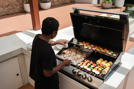 Chef is preparing barbeque for the guests of a luxury villa.