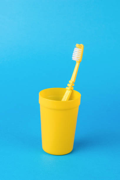 istock A yellow glass with a yellow toothbrush on a light blue background. 1435176448