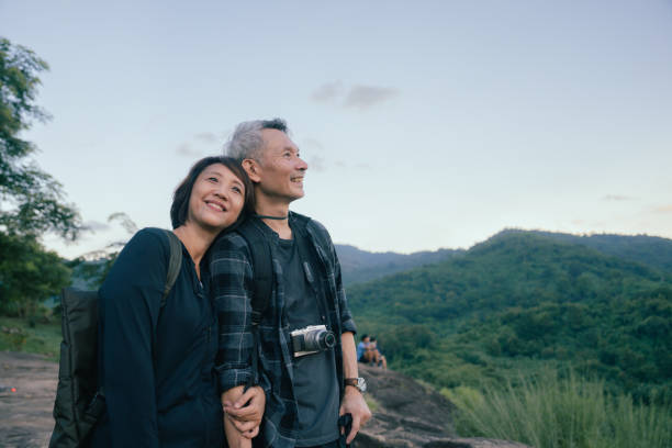 This is my life. Happy Asian couple hikers on top of the mountain enjoying sunset over the tropical valley. green environment friendly stock pictures, royalty-free photos & images