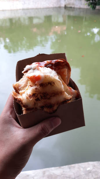 istock Hand holding Egg Toast with sauce and mayonnaise on fish pond background 04 1435202559