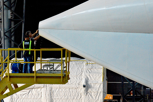 Dulles, Virginia, USA - April 23, 2012: Workers inspect the end of the tail cone covering the engines of the Space Shuttle Discovery as they prepare to remove the protective device.
