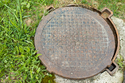 Steel manhole cover. Sewerage in city. Hatch in ground.