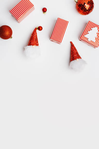 istock New Year holiday frame from Christmas decorations on white background, red wrapped gift box, funny dwarfs, Christmas mirror ball, wooden fir tree, aesthetic festive concept, top view 1435208008