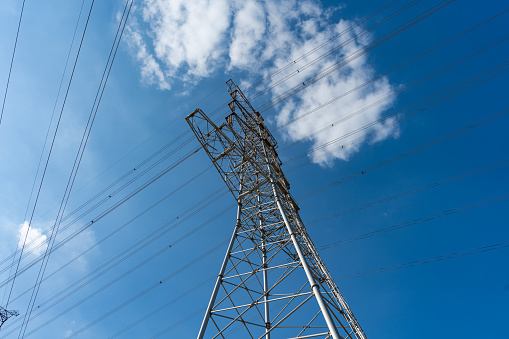 Transmission tower under blue sky and white clouds