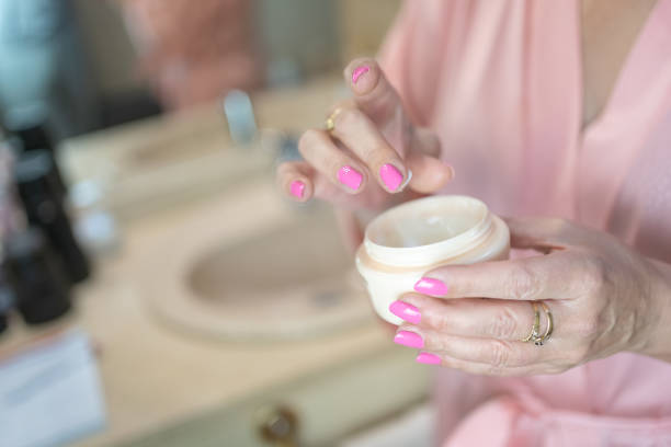istock Senior woman's hand taking cream from a bottle for skin care and hydration. 1435210374