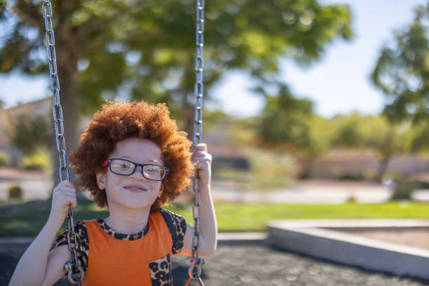 A portrait of a happy African American child with albinism having fun on the swings.
