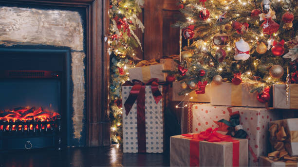istock Christmas gifts under decorated tree in dark room illuminated with fire from fireplace 1435215033