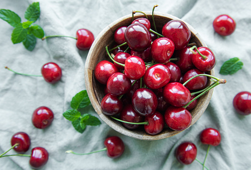 Fresh red cherries fruit in bowl on a green textile background