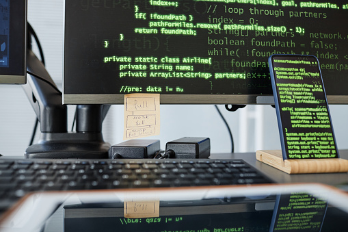 Close up of programmers workplace with computers keyboard and green code lines on screen