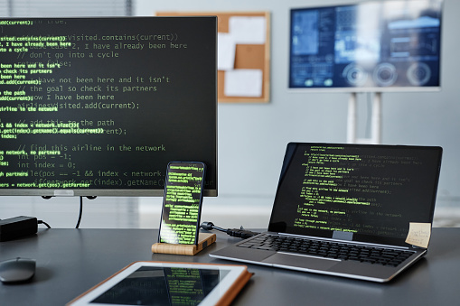 Background image of computer screens with green code lines at programmers workplace