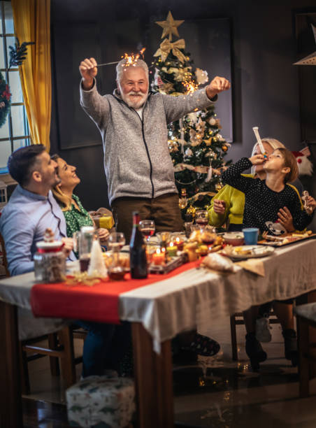 la familia feliz está cenando en casa, celebración de vacaciones de navidad - los niños y los padres brindis bebidas mientras almuerza fotografías e imágenes de stock