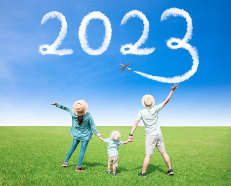 Happy New year 2023 concept. Happy family watching the cloud drawing by airplane in sky
