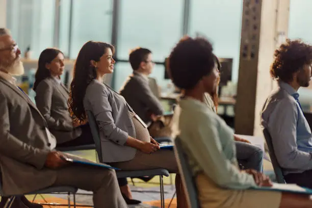 Photo of Happy pregnant businesswoman attending a seminar in board room.