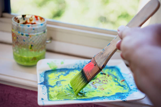 Little girl at home painting with multicoloured water-colour drops
