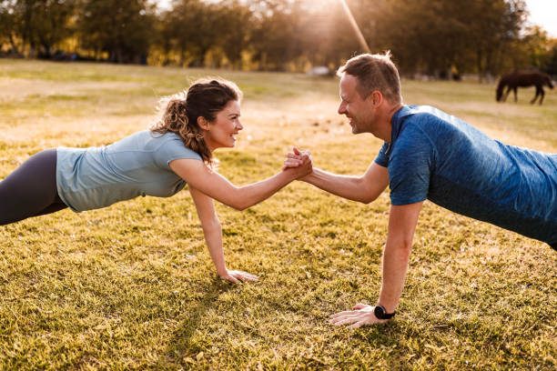 Happy athletic couple cooperating while exercising strength in nature.