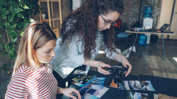 istock Creative colleagues placing pictures on table and shooting flat lay while talking about designing project. Top view of modern table with illustrations. 1435224920
