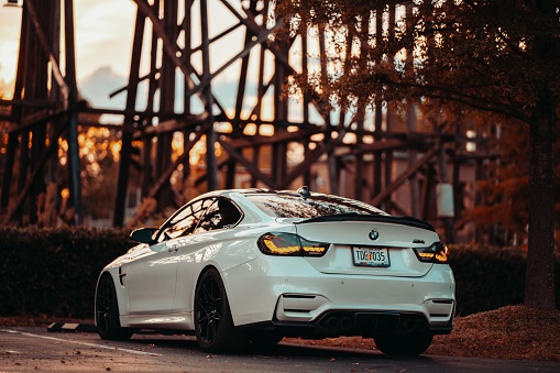 Tuscaloosa, United States – October 09, 2022: A white BMW M4 parked in front of a bridge