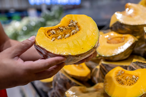 Cropped image of man's hand choosing pumpkin in supermarket. Concept of healthy vegetarian food.